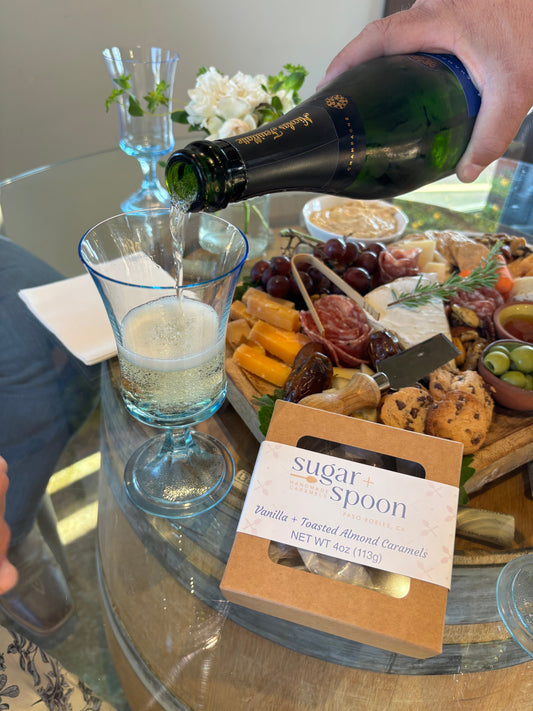 A summer charcuterie board with cheese, fruit, wine, and handmade caramels for dessert.