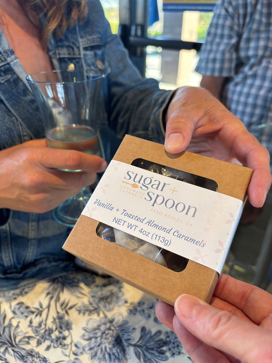 A box of handmade caramels shared at a summer dinner party with wine, fruit, and a charcuterie board.