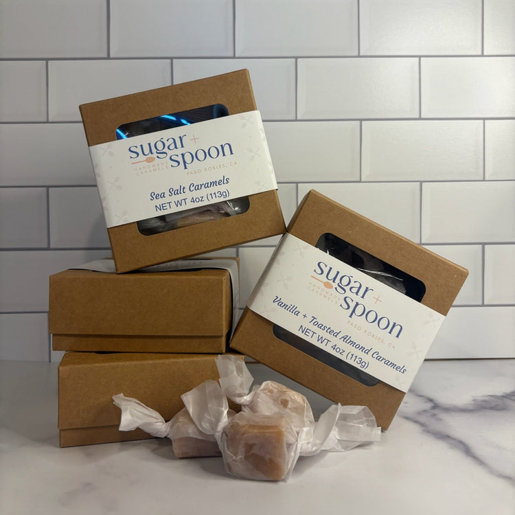 Boxes of 'Sugar Spoon' caramel candies on a marble surface with a tiled wall background